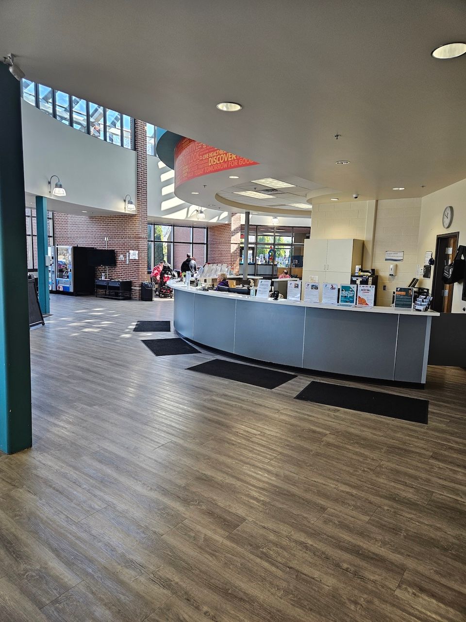 A large lobby with a curved counter and wooden floors.