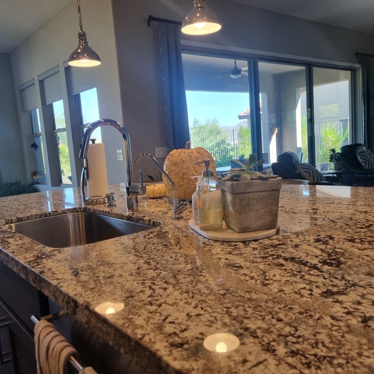 Kitchen island with granite countertop, sink, pendant lights, and sliding glass doors to a patio.