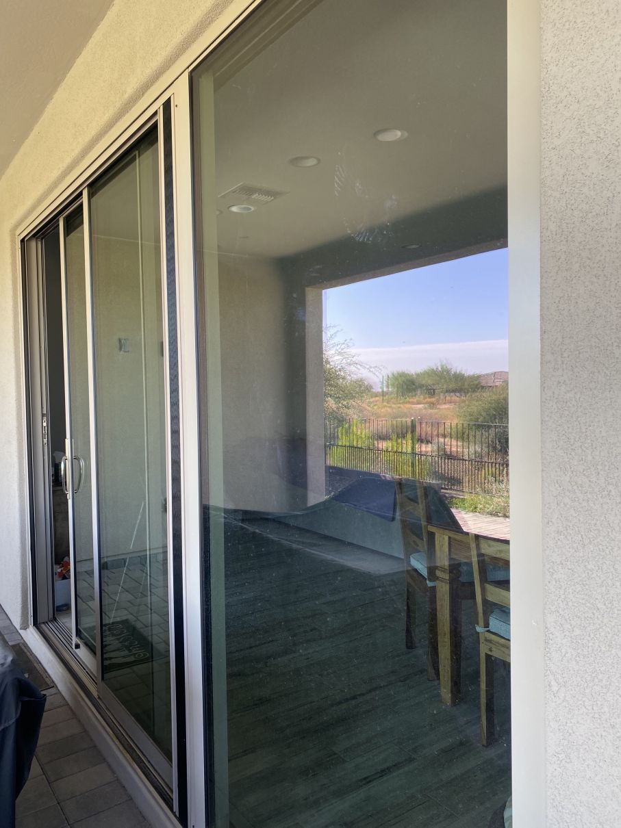 Sliding glass doors open to a balcony with a chair and desert landscape beyond.