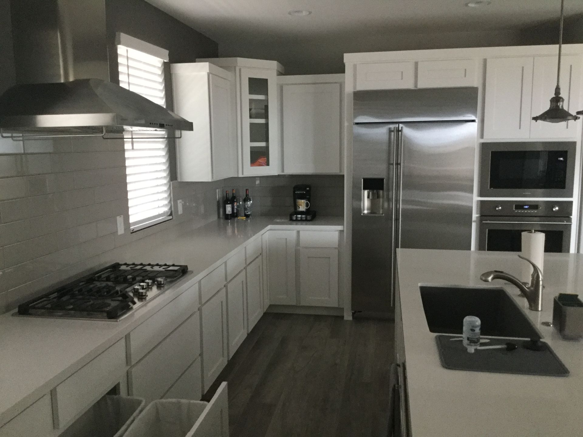 Modern white kitchen with stainless steel appliances, dark countertops, and a black island sink.