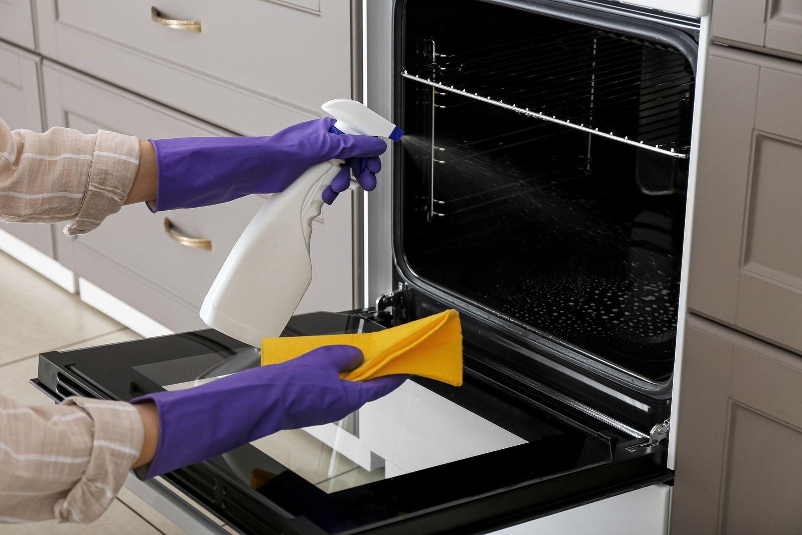 Yellow-gloved hand cleaning a white toilet bowl with a brush in a bathroom