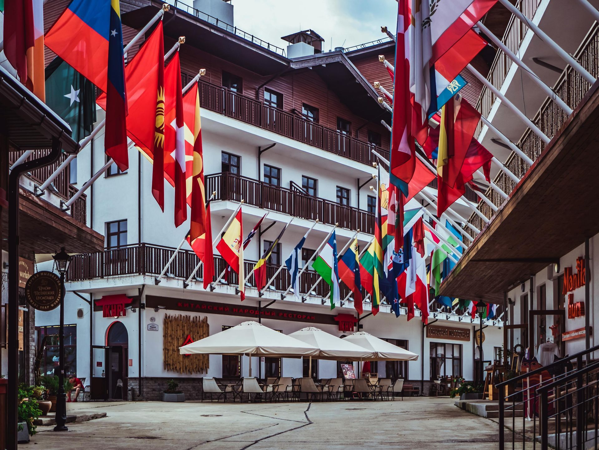Hotel courtyard lined with flags; cafe tables with umbrellas; multi-story building.