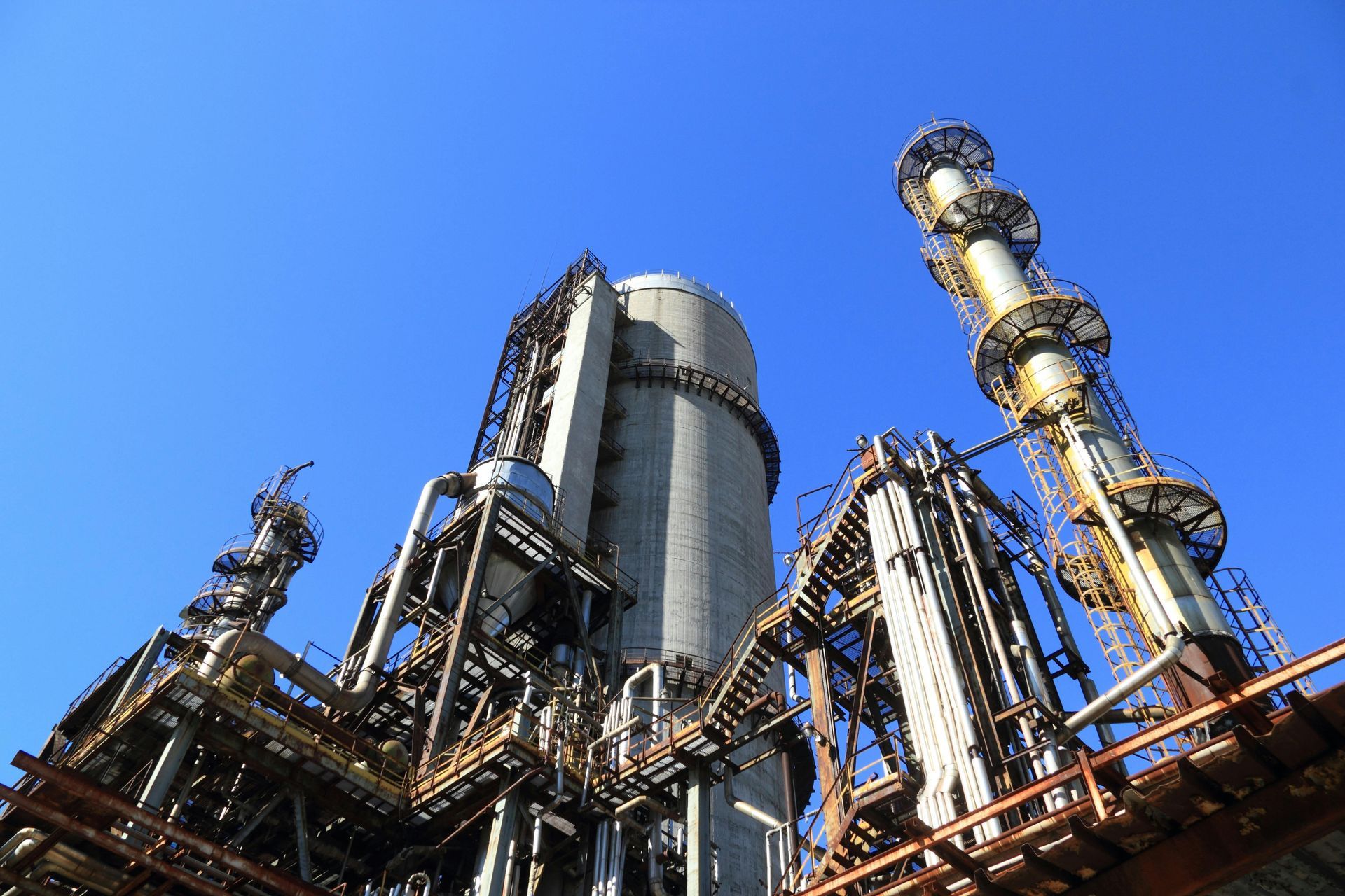 Industrial plant with tall towers and pipes against a blue sky.