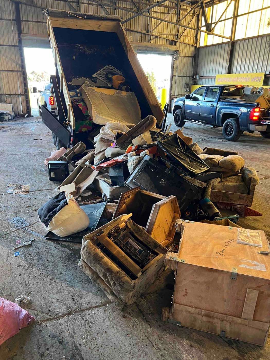 Dump truck unloading debris inside a large industrial building.
