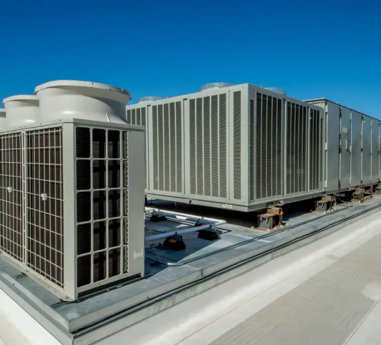 Large industrial HVAC units on a flat building rooftop under a clear blue sky.