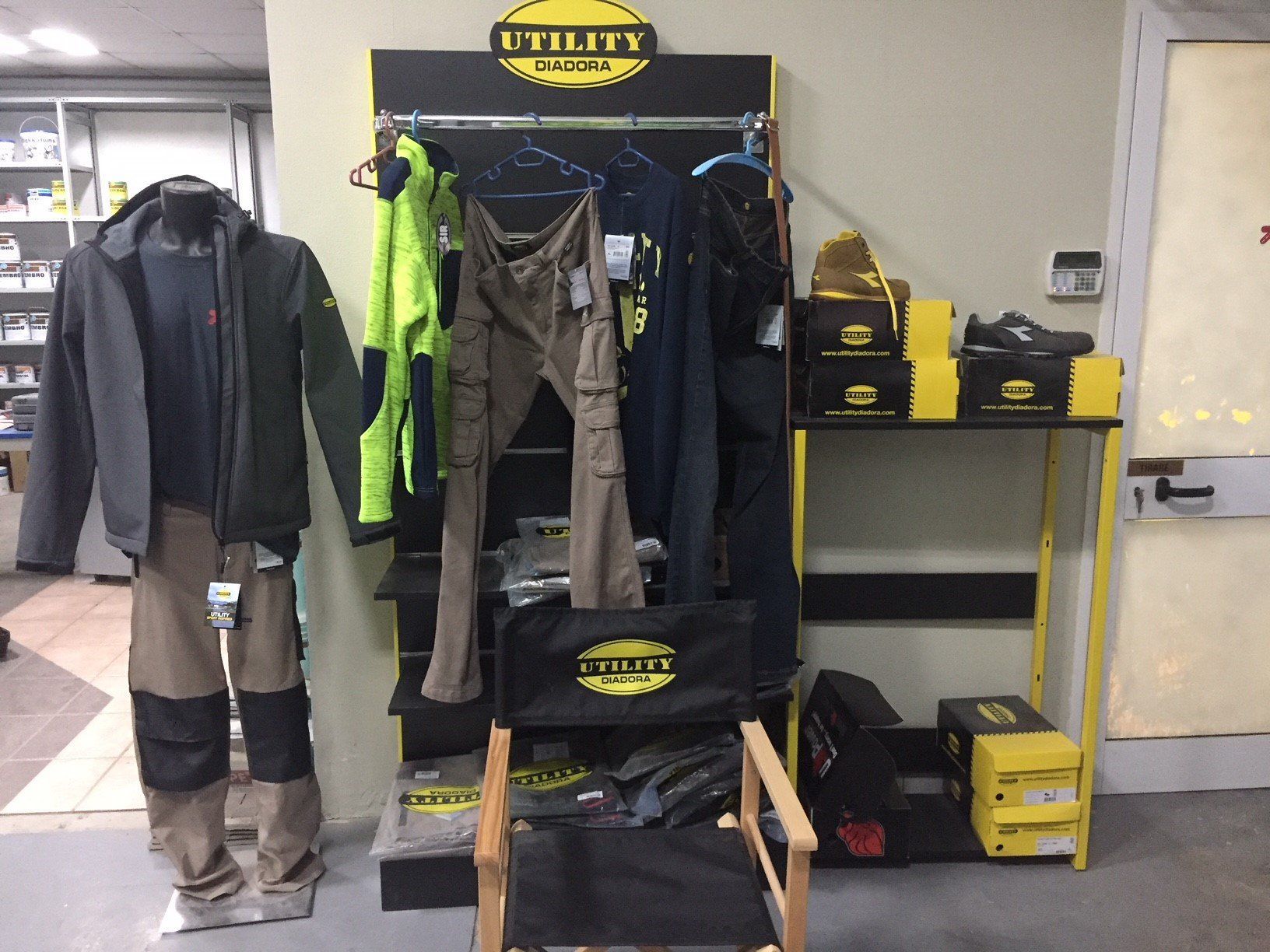 Esposizione di abiti da lavoro e scarpe con un manichino, uno scaffale e delle scatole in un negozio.