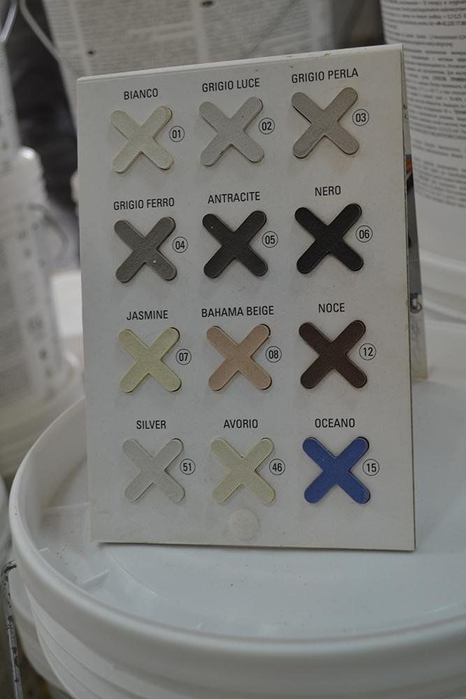 Esposizione di campioni di colori di dodici diverse tonalità di vernice: bianco, grigio e marrone, più blu.