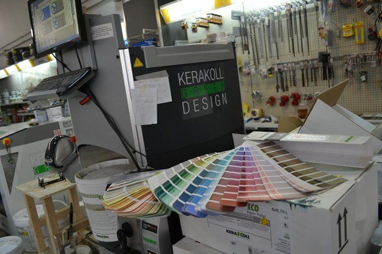 L'interno di un negozio di vernici con campioni di colore, una macchina Kerakoll Design e utensili sulla parete.