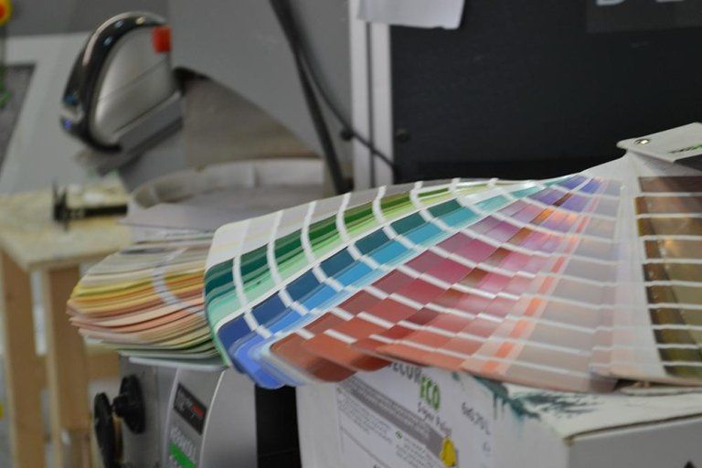 Campioni di colori di vernice disposti a ventaglio su una scatola, che mostrano una gamma di tonalità.