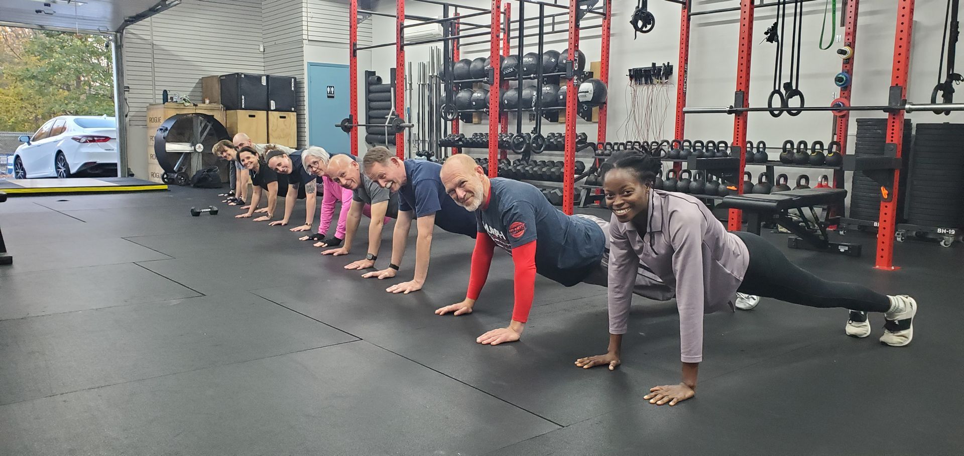A group of women are squatting with kettlebells in a gym.
