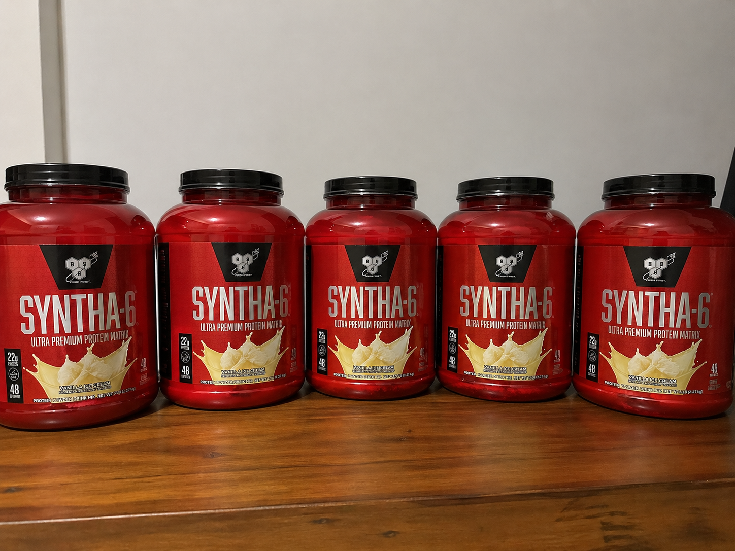Bote rojo de proteína en polvo Syntha-6 con tapa negra y detalles en etiqueta beige.