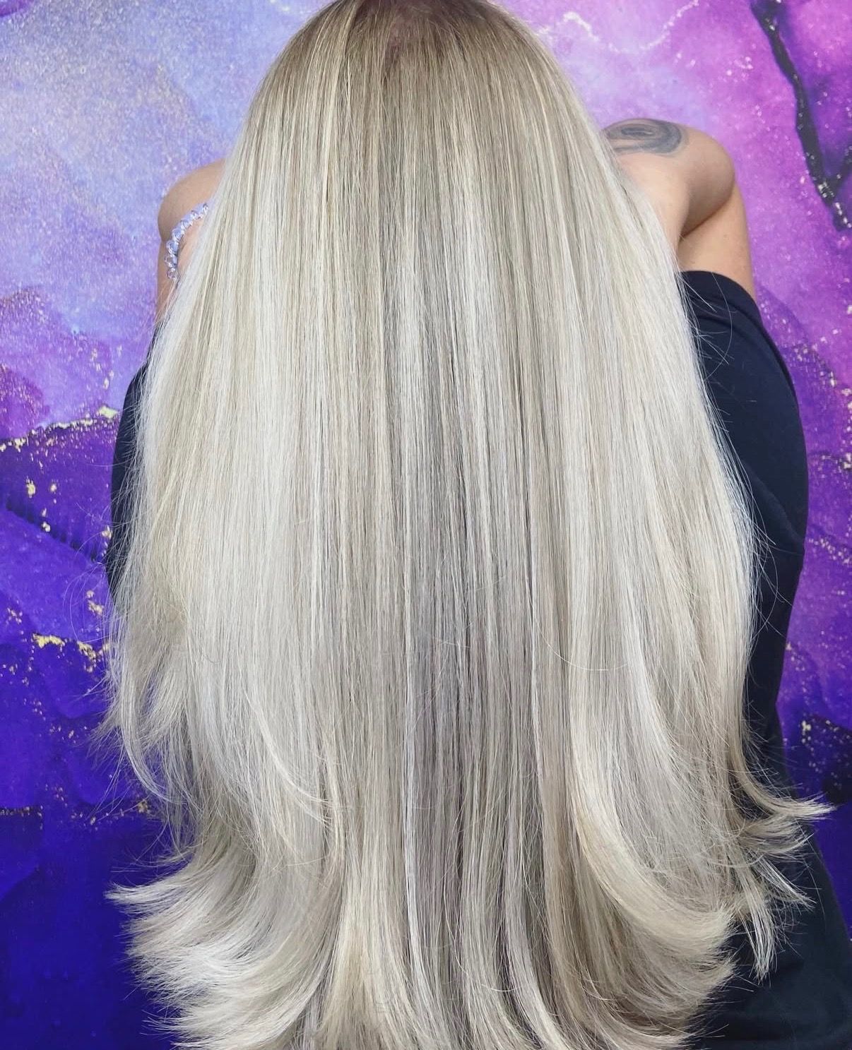 Long, light blonde hair cascading down back, with purple and gold background.