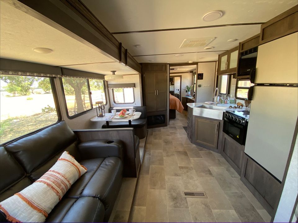 Cozy, modern camper interior featuring a kitchen, seating area, and sunlight streaming through windows.