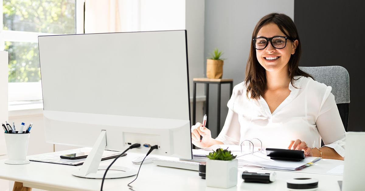 Eine Frau sitzt an einem Schreibtisch vor einem Computer.