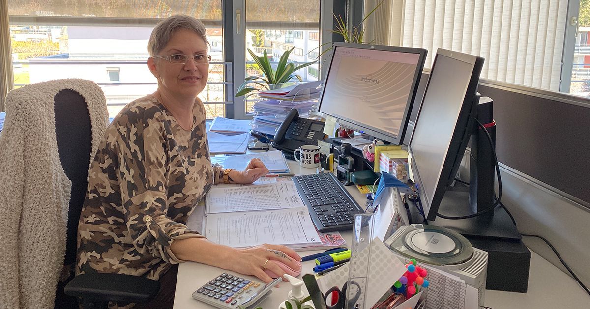 Eine Frau sitzt an einem Schreibtisch vor zwei Computerbildschirmen.