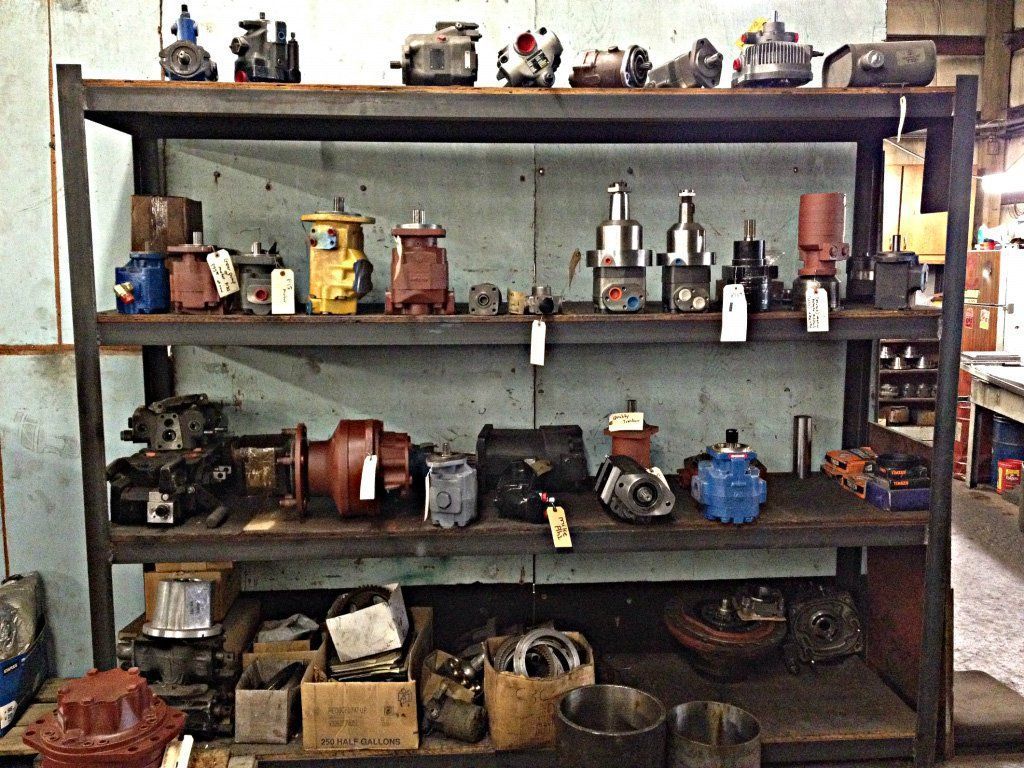 Shelves of hydraulic pump components in a workshop setting.