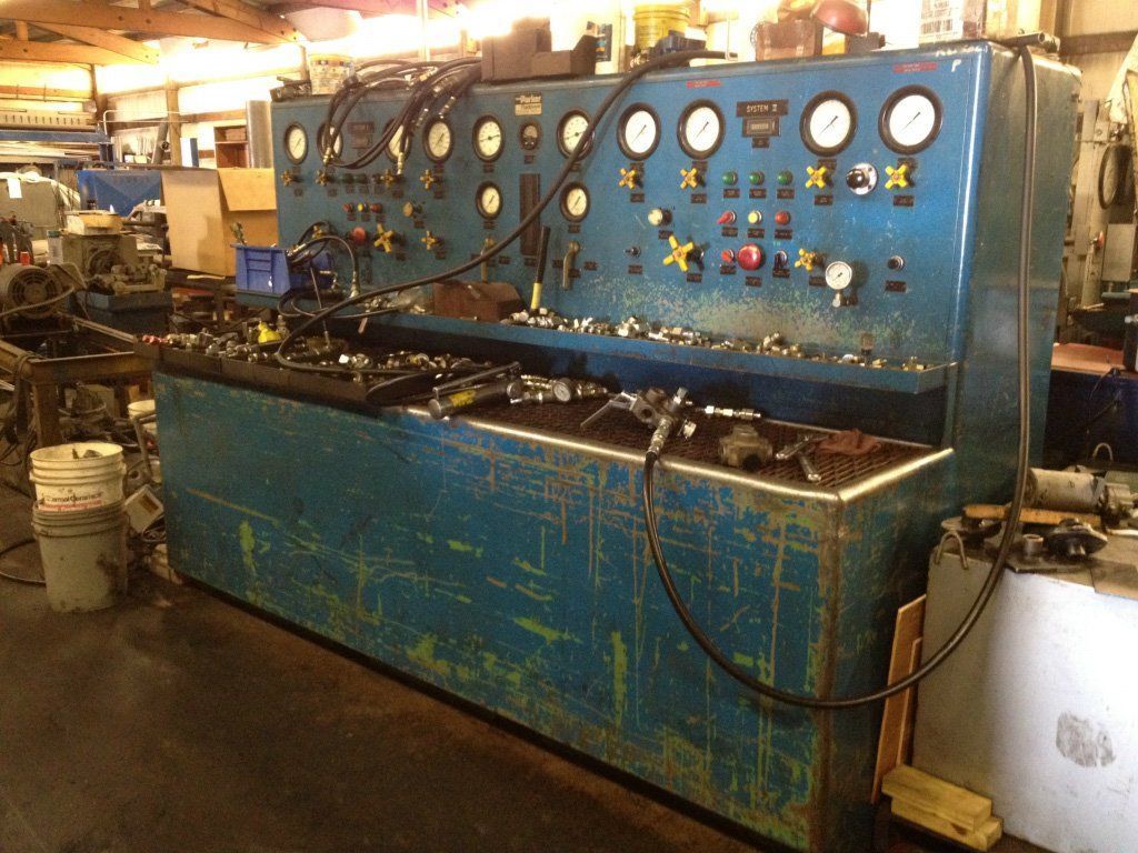 Blue industrial machine with gauges and dials in a workshop setting.