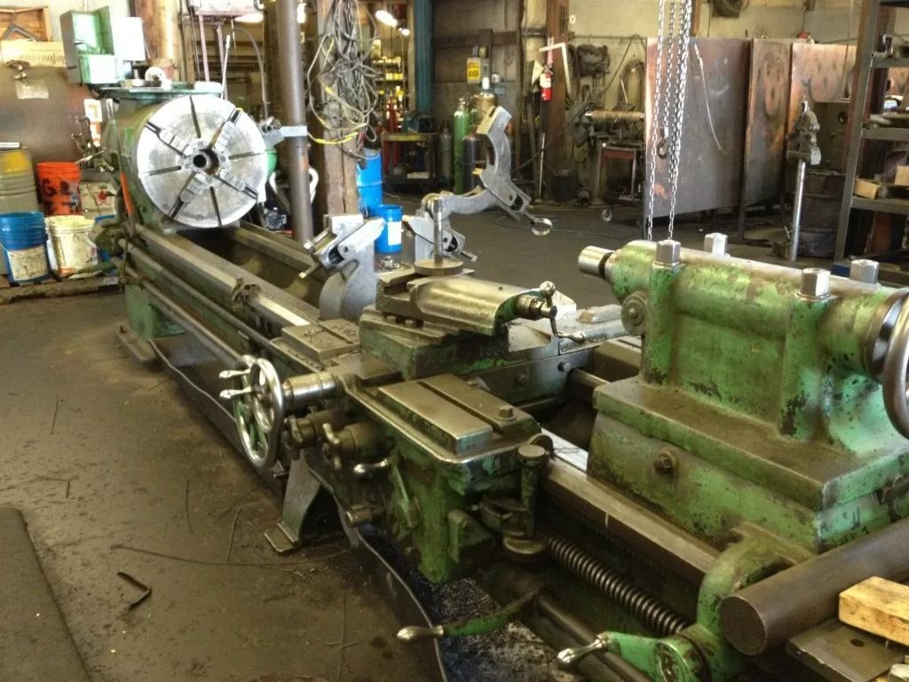 Long, green metal lathe machine in a workshop setting.