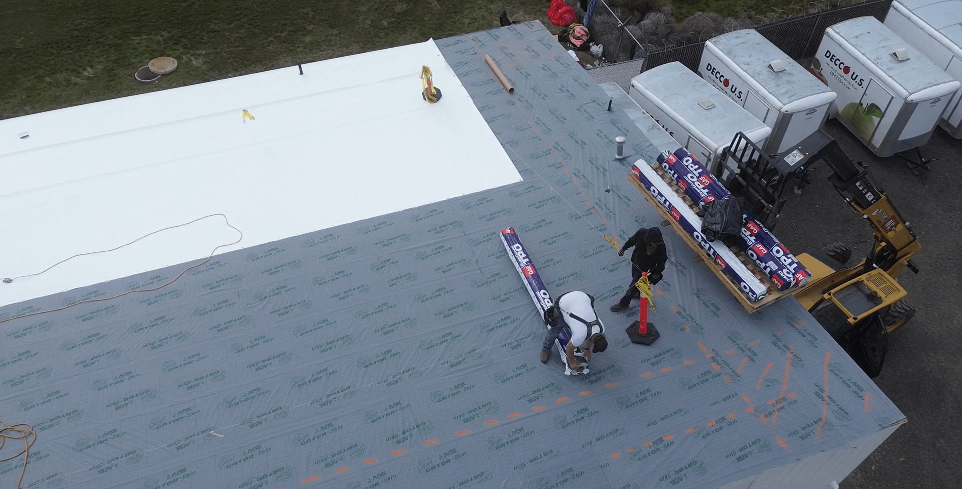Yakima Roofing & Remodeling crew installing TPO roofing membrane on resheeted OSB substrate at Decco USA in Yakima.