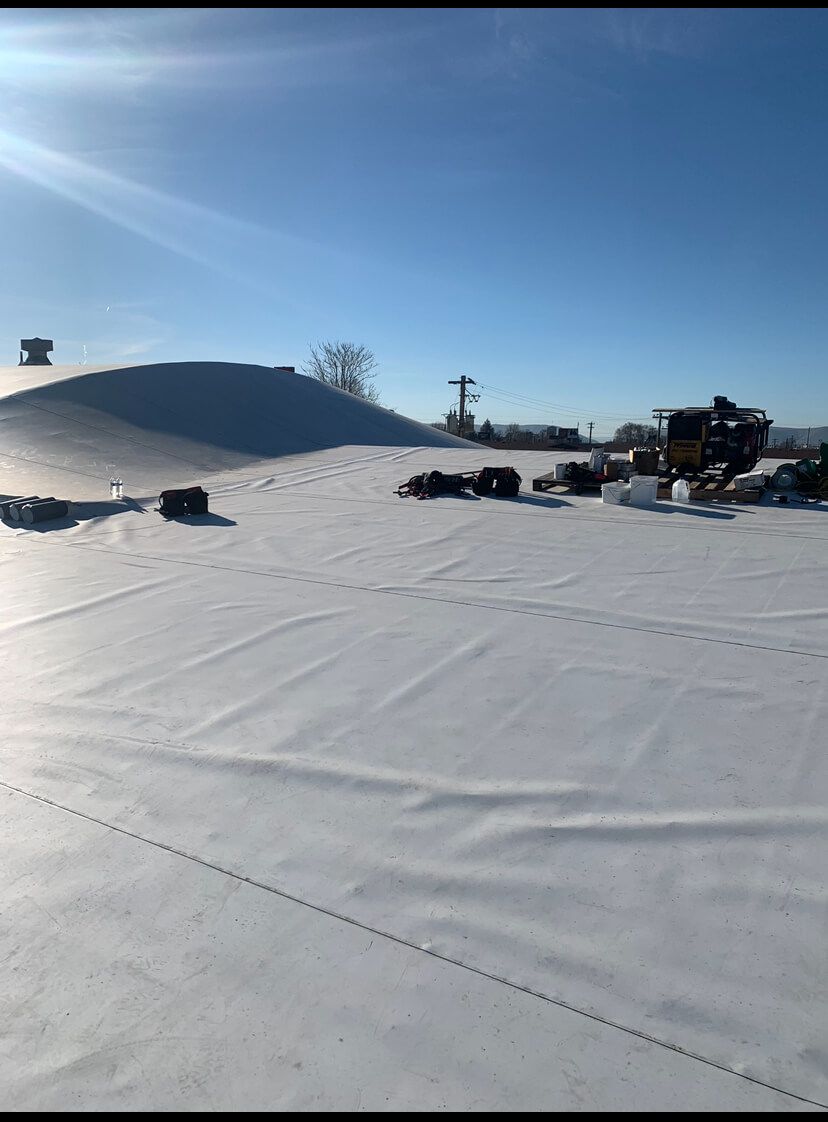 Completed TPO roof section with visible tools and equipment at Decco USA in Yakima, installed by Yakima Roofing & Remodeling.