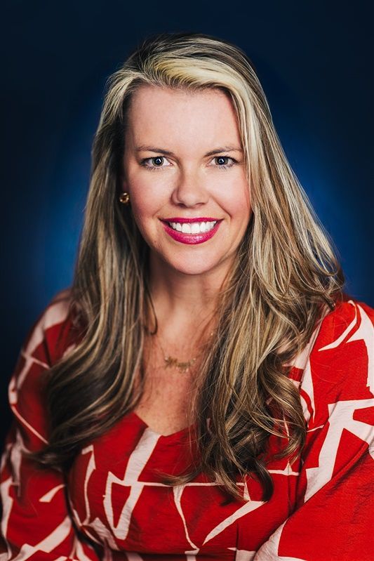 A women in a red and white dress is smiling for the camera.
