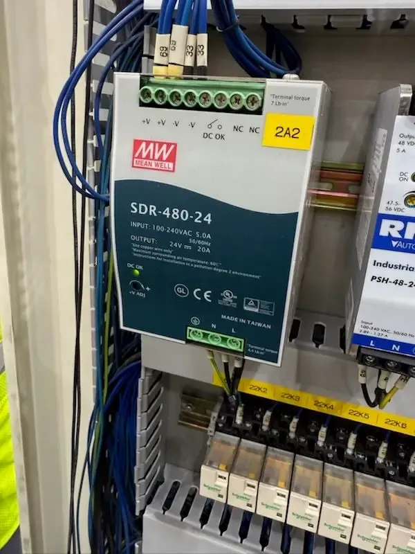 A Mean Well SDR-480-24 power supply mounted in an electrical panel with connected wires.