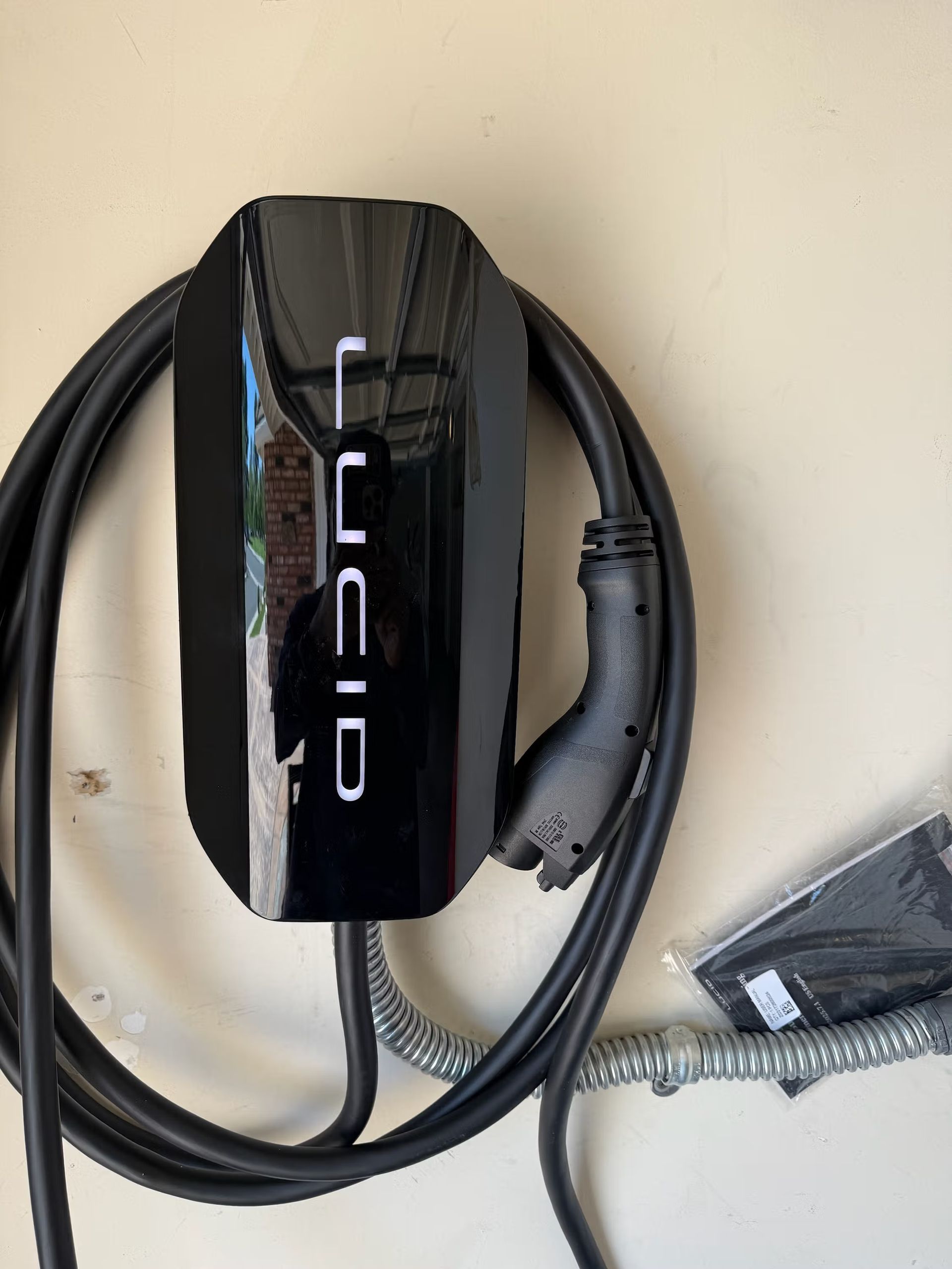 Lucid EV charger mounted on a beige wall, with a black charging cable and plug.