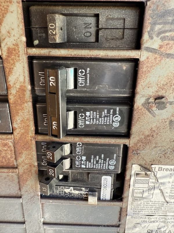 Electrical panel with multiple circuit breakers, some labeled 