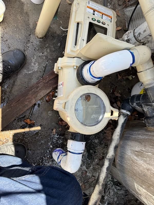 Pool equipment with pipes and electrical components, outdoors.
