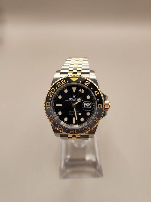 A rolex watch is sitting on top of a clear display case.