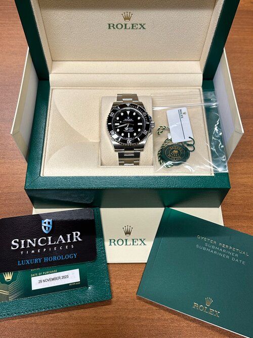 A rolex watch is in a box on a wooden table.