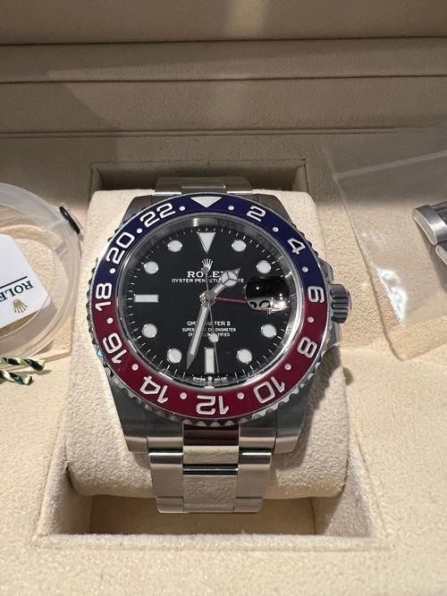 A rolex watch is sitting on a white cushion in a box.