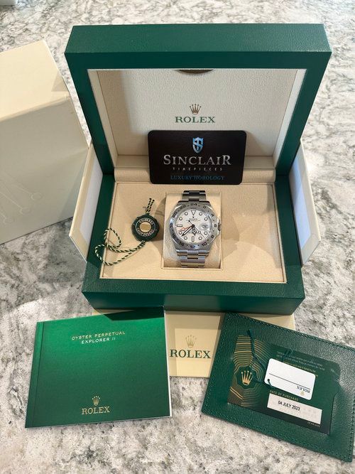 A rolex watch is in a green box on a table.