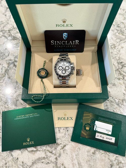 A rolex watch is in a green box on a counter.