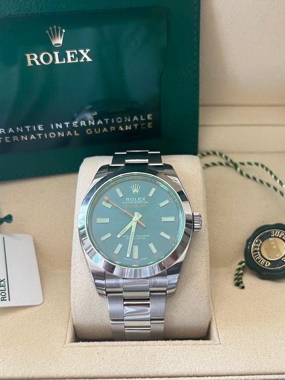 A rolex watch with a green face is in a box