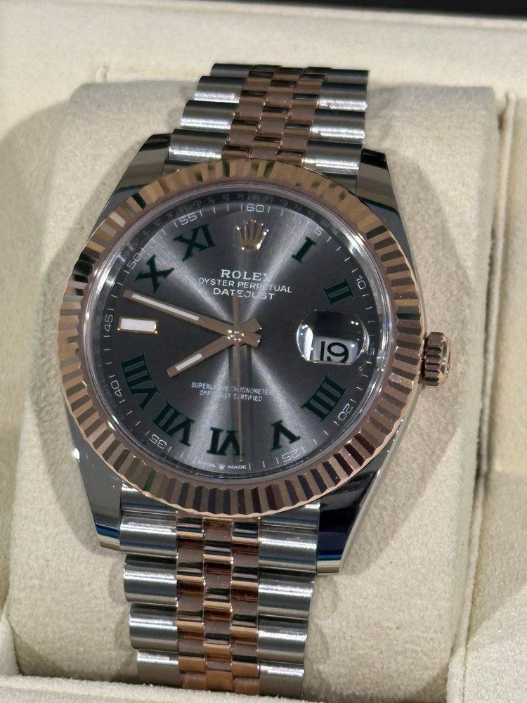 A silver and rose gold rolex watch with roman numerals