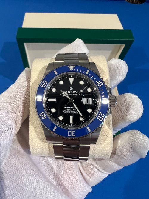 A person wearing white gloves is holding a rolex watch