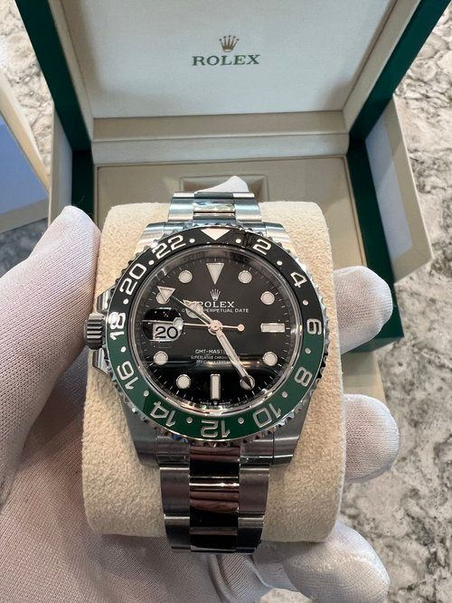 A person is holding a rolex watch in front of a box