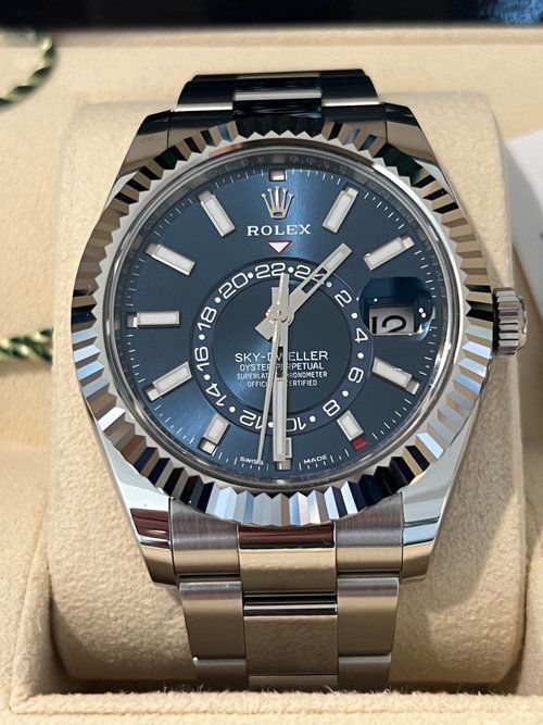 A silver rolex watch with a blue face is in a box