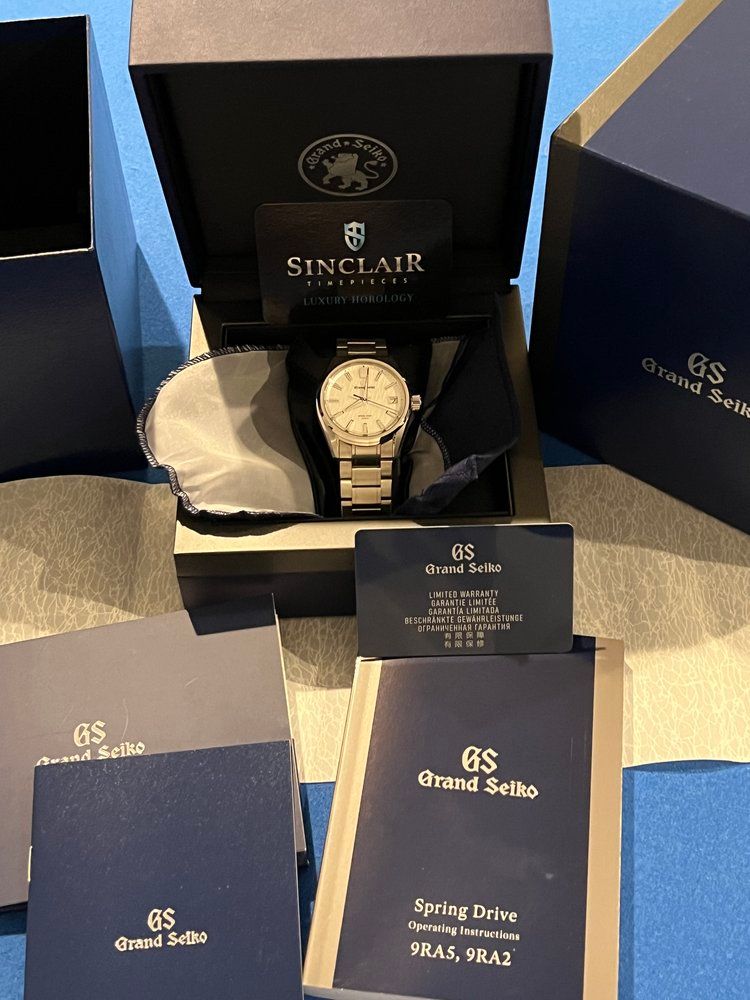 A sinclair watch is in a box surrounded by papers