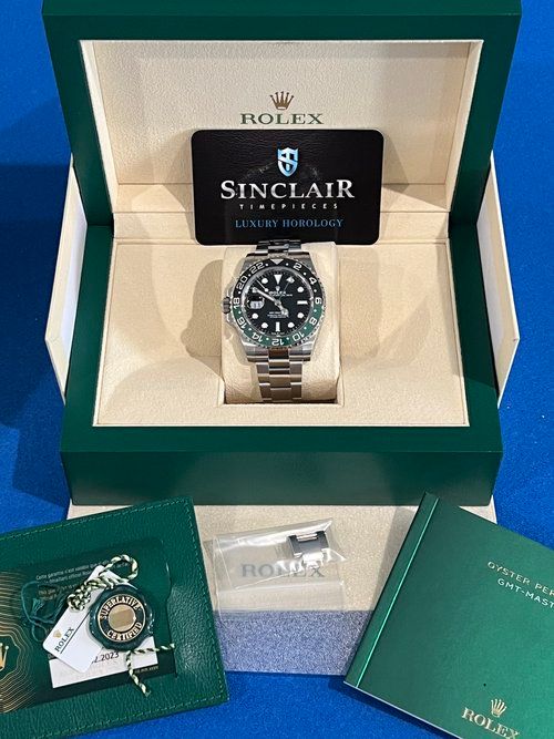 A rolex watch is in a green box with a certificate.
