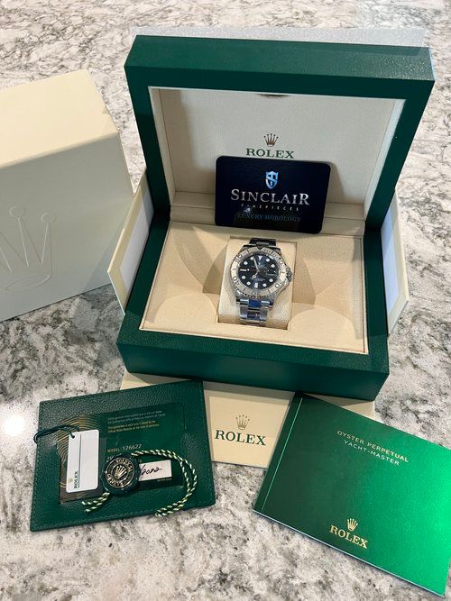 A rolex watch is in a green box on a counter.