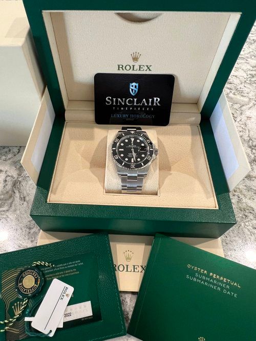 A rolex watch is sitting inside of a green box.