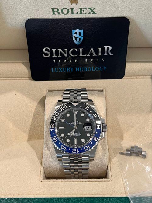 A rolex watch sits in a box next to a sinclair card