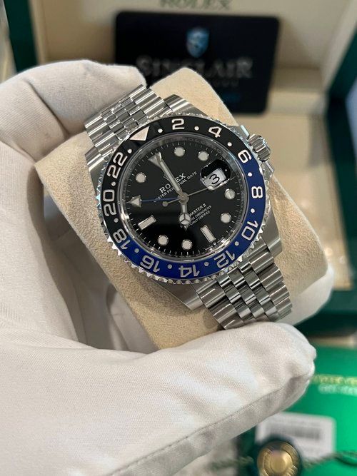 A person is holding a rolex watch in their hand.