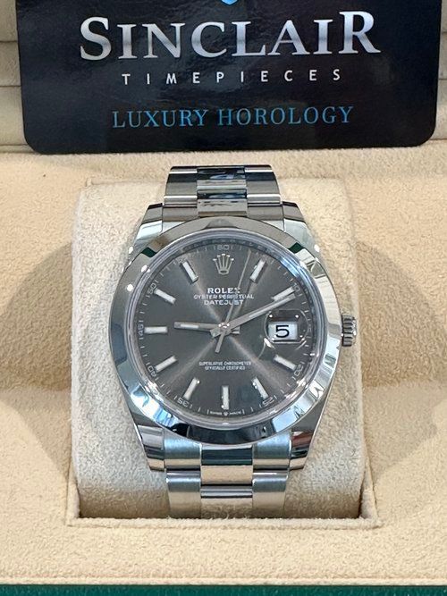 A rolex watch is in a box with a tag attached to it.
