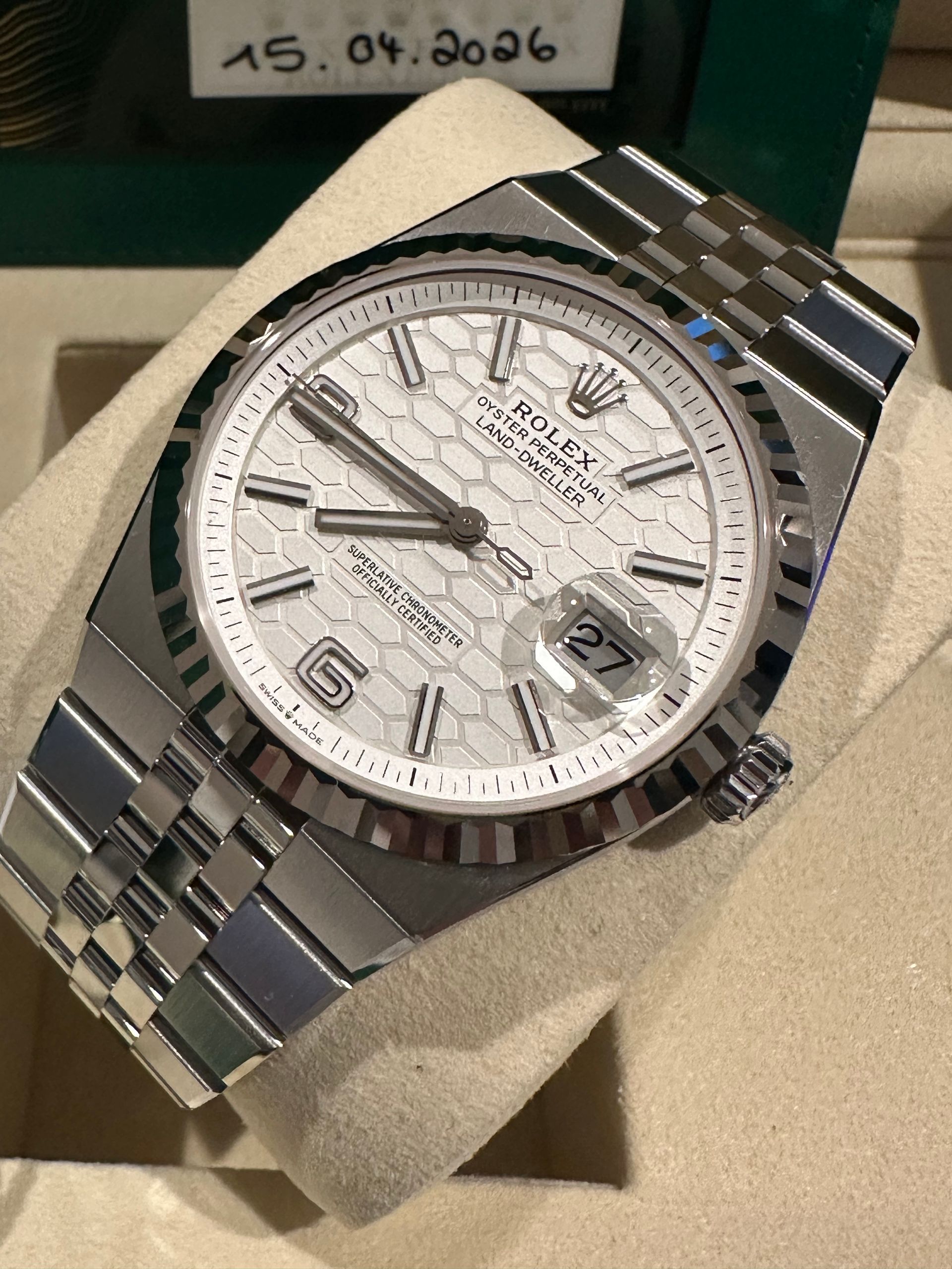 A rolex watch is sitting on top of a white cushion.