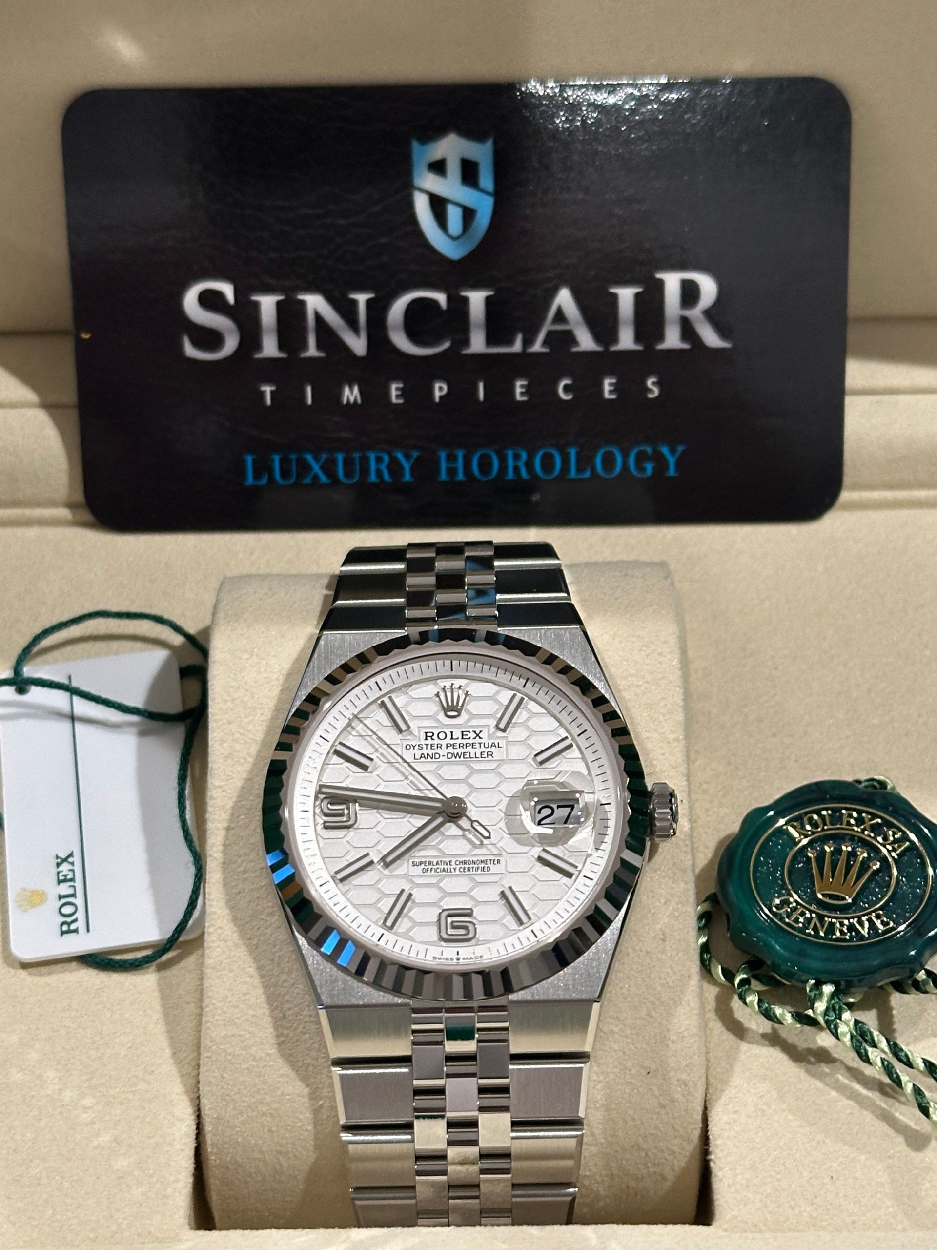 A rolex watch is in a green box on a table.