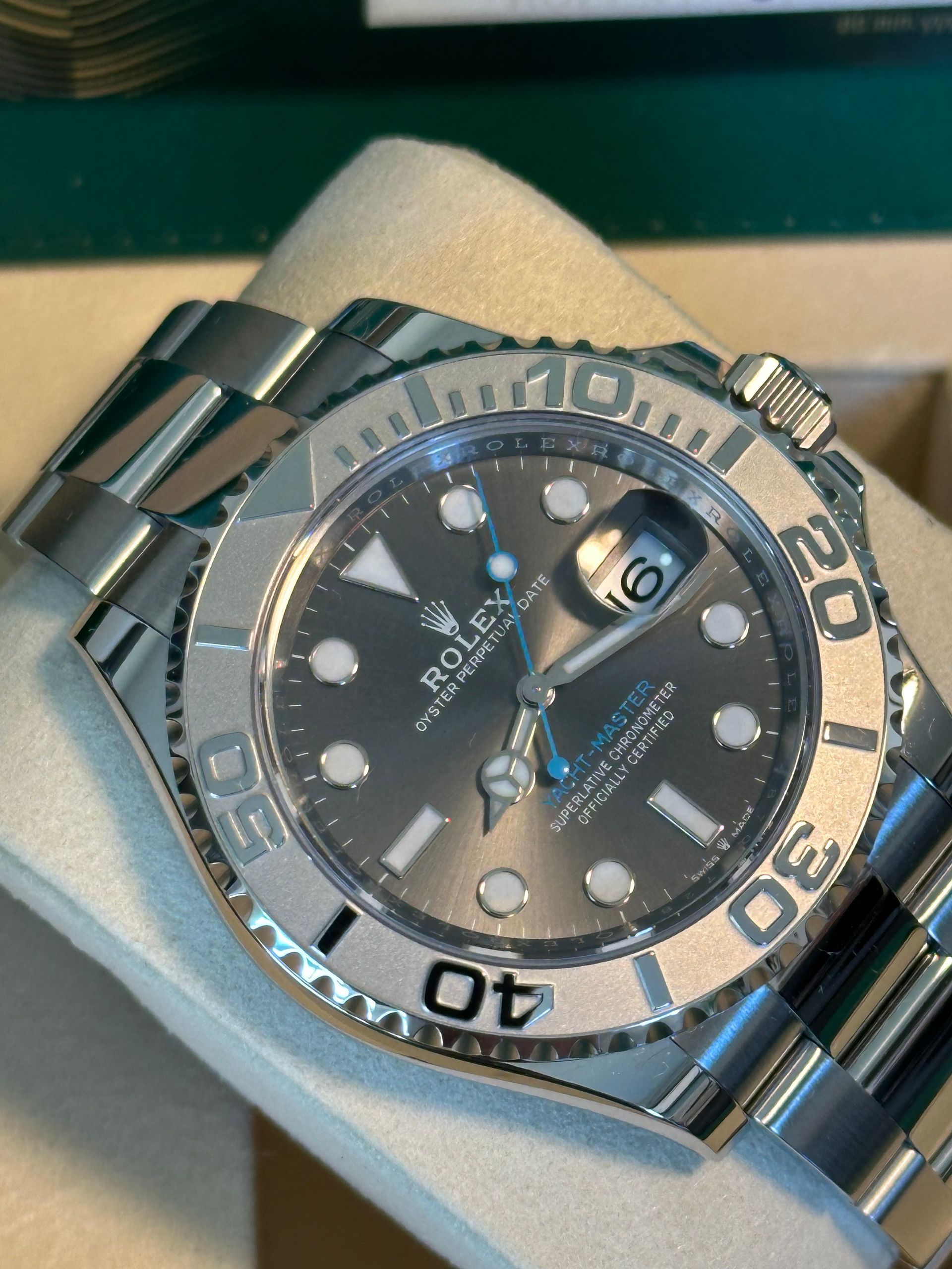 A silver rolex watch sits in a box