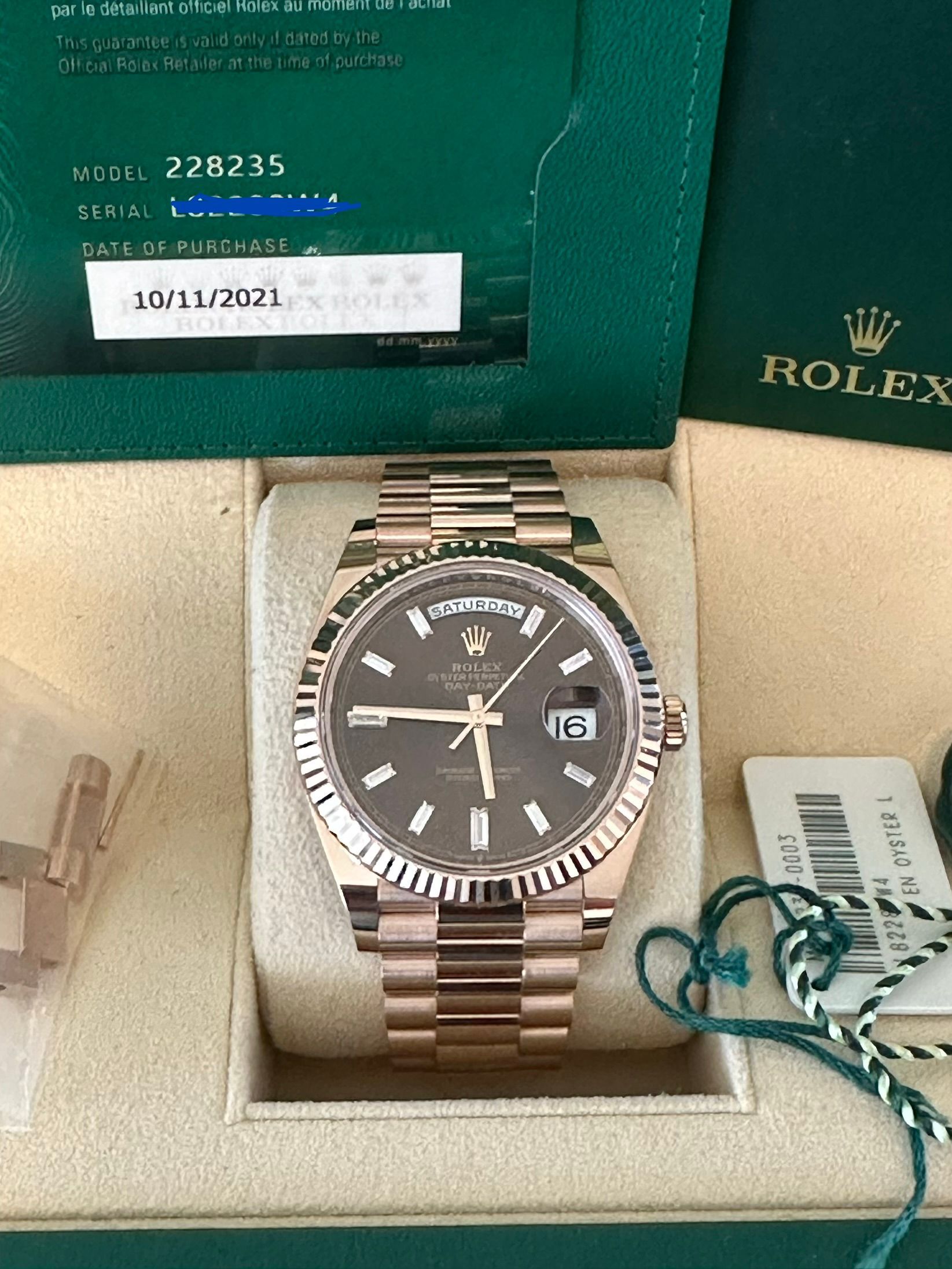 A rolex watch is in a green box on a table.